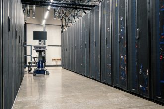 Armários metálicos com servidores, equipamentos de rede e cabos em um data center moderno.