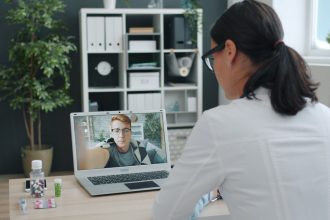 Médico participa de uma consulta de saúde por videochamada com uma paciente.