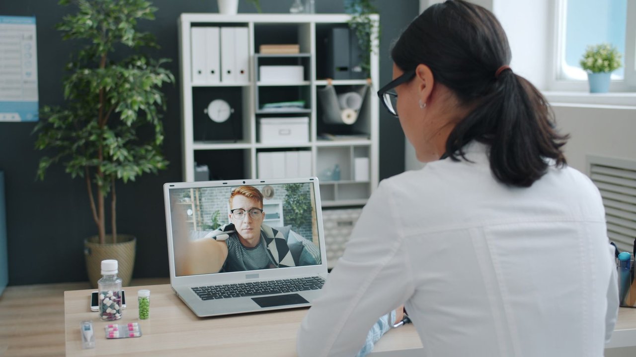 Médico participa de uma consulta de saúde por videochamada com uma paciente.