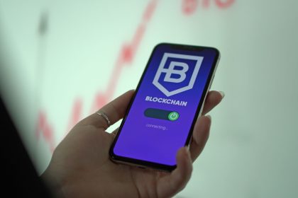 Mão segurando um smartphone com a tela de uma carteira de criptomoedas baseada em blockchain
