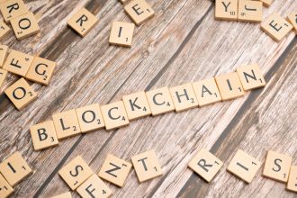 Peças de madeira formam a palavra “blockchain” sobre uma superfície de madeira.