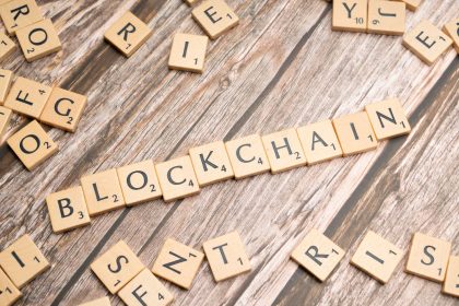 Peças de madeira formam a palavra “blockchain” sobre uma superfície de madeira.